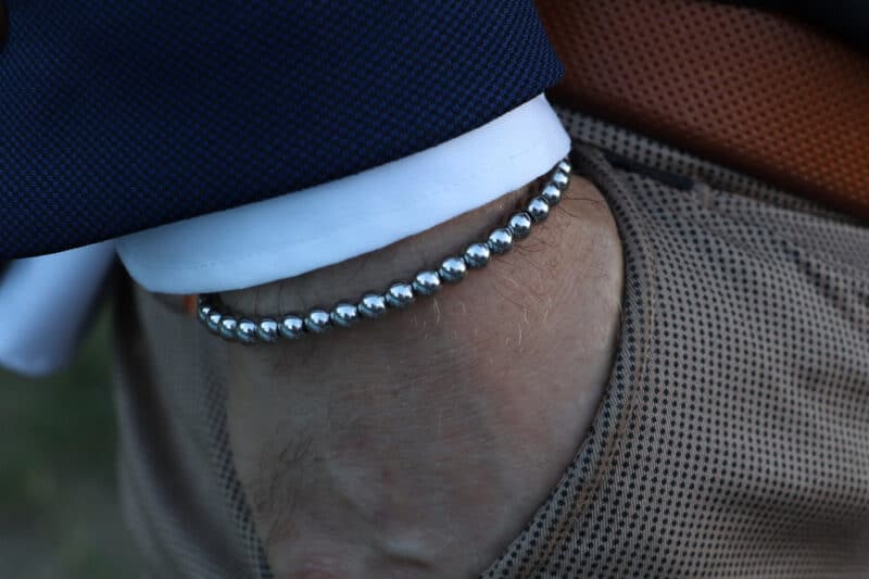 3Bello Surfers Wave armband met zilveren edelstalen kralen, gedragen bij donkerblauw overhemd en grijze broek