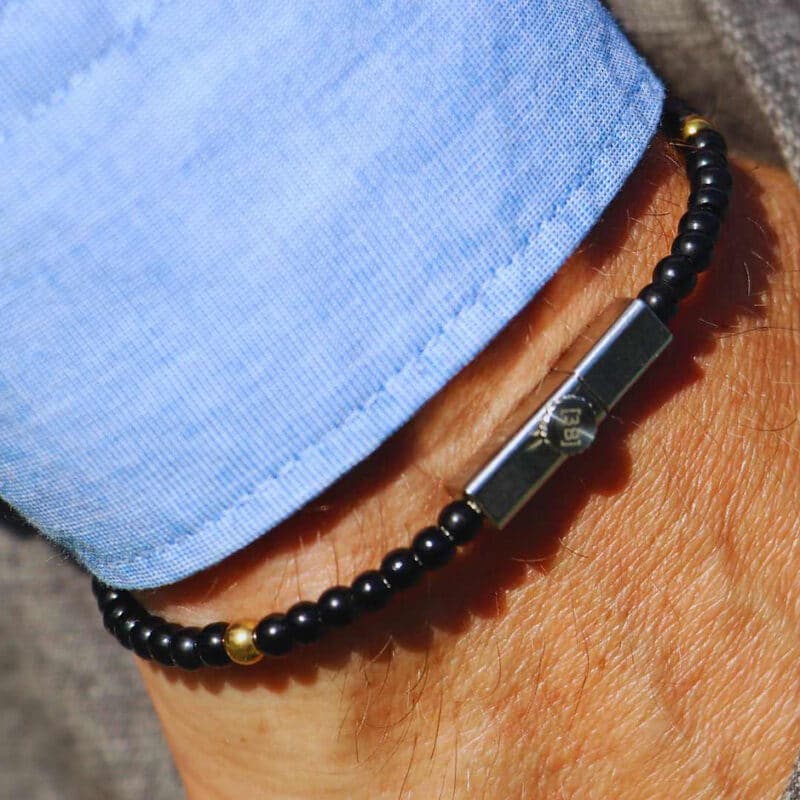 3Bello Wave Line armband met zwarte kralen, gouden accent en zilveren sluiting, gedragen bij lichtblauw overhemd